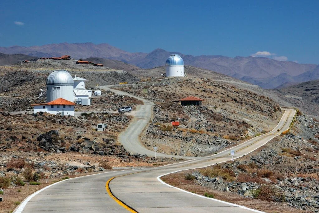 A view of the “Polish” section of Las Campanas Observatory in Chile. To the left are the control room and dome of the Warsaw University Telescope; to the right stands the observers’ cottage with its dark walls and red roof. Above it is the Henrietta Swope Telescope, where the OGLE project began before the Warsaw University Telescope was built. Photo: Ewa Zegler-Poleska