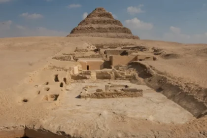 A view of the excavation site. In the foreground is the edge of the Dry Moat; in the background is the Step Pyramid; between them are the remains of the tombs of the Lower Necropolis (on the right) and the pits where the burials of the Upper Necropolis were located.